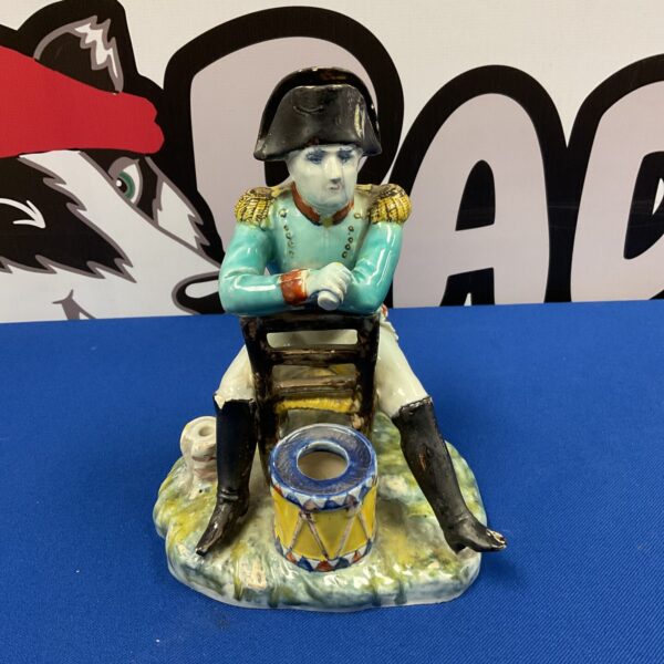 Antique 19th-century Napoleon inkwell figurine on blue background.