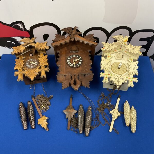 Lot of three vintage German cuckoo clocks with detailed carvings.