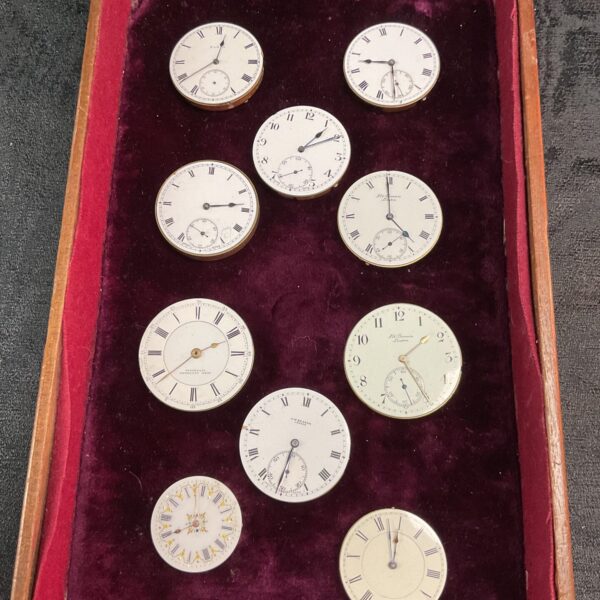 Tray of antique pocket watch movements for repair or collection.