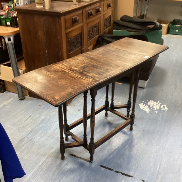 Side view of antique oak gate leg table with folding leaves.