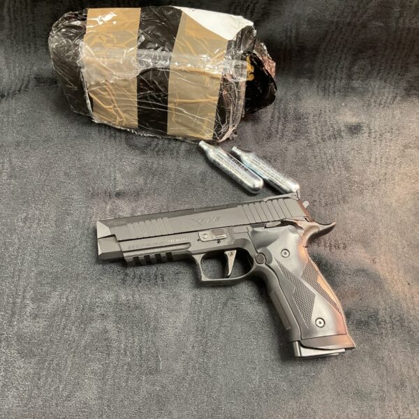 Sig Sauer Xfive .177 Co2 pistol with spare cartridges displayed.