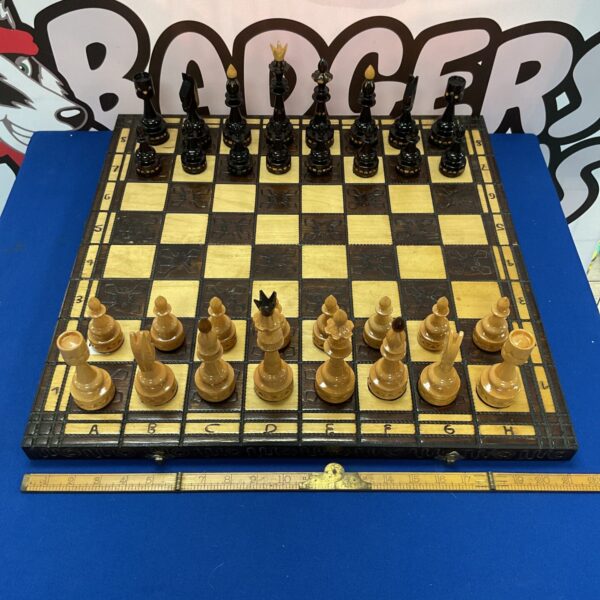 Antique carved wooden chess set with detailed chessmen on board.