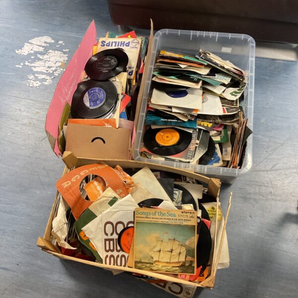 Vintage 7 inch vinyl records in a box, a collection of music singles.