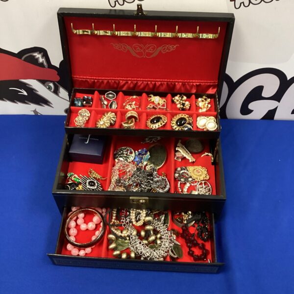 Vintage jewellery box overflowing with silver and costume jewellery.