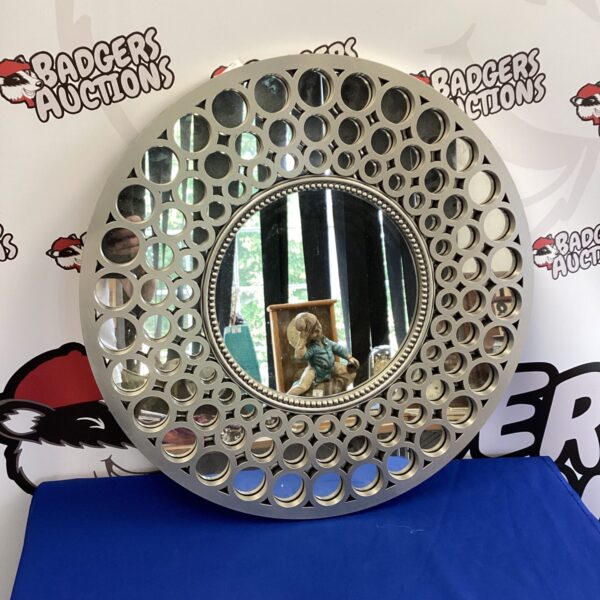 Round decorative wall mirror with cut-out details.