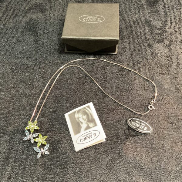 Close-up of Donny B silver necklace with butterfly and floral pendant.