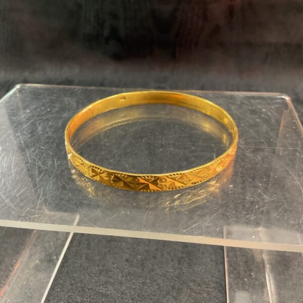Vintage gold bracelet with textured pattern and yellow gold tone.