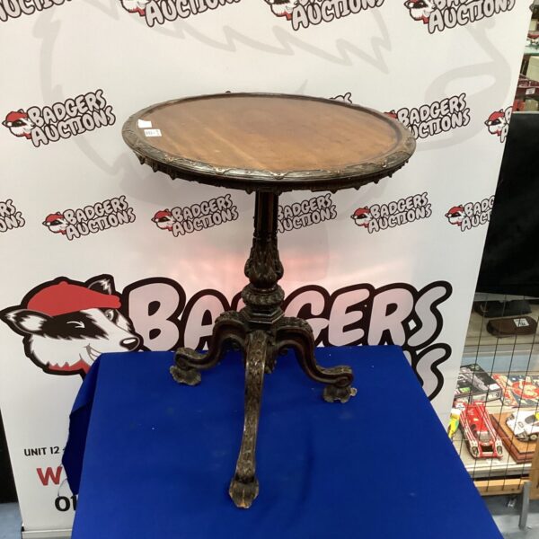 Vintage three-legged side table with carved details and circular top.