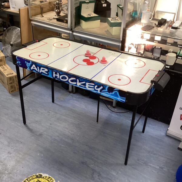 Blue tabletop air hockey table with red strikers and puck.