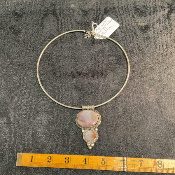 Close-up of a moss agate choker necklace with a swirling green pendant.