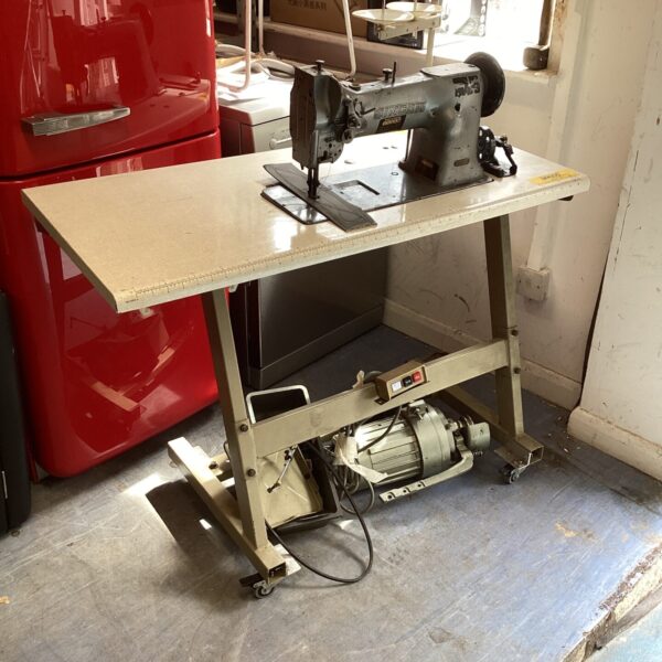 Vintage Singer industrial sewing machine on metal table.