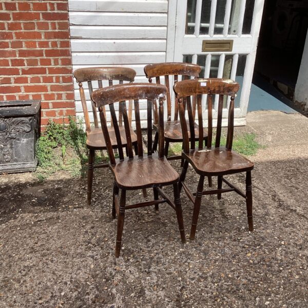 Four vintage oak kitchen chairs in a rustic setting.