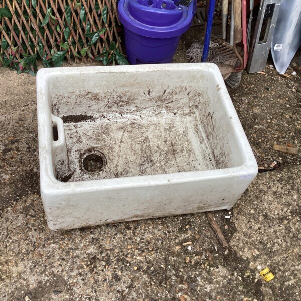 Vintage Belfast sink repurposed as a garden planter in a backyard setting.