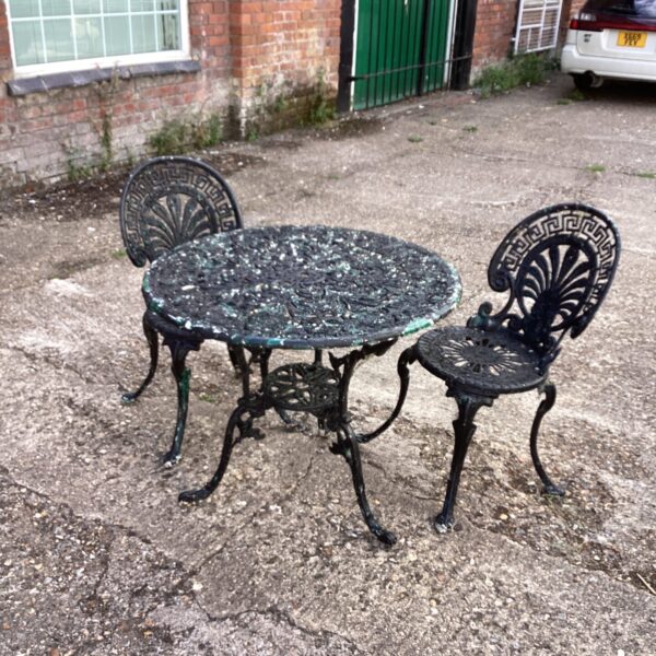 Vintage metal garden table and chair set with floral details.