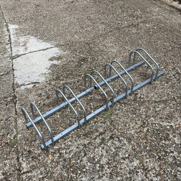 Metal bike rack holding five bicycles for secure outdoor storage.