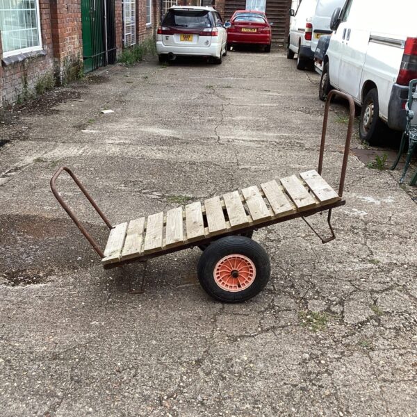 Vintage two-wheeled cart with wooden platform and metal frame.