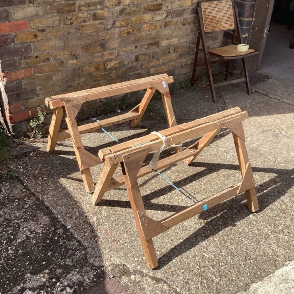 Pair of vintage wooden trestles in a garden setting.