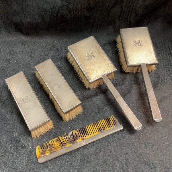 Antique silver Art Deco dressing table brush set displayed.