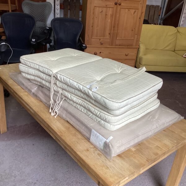 Stack of four patio chair cushions and one sun lounger cushion.