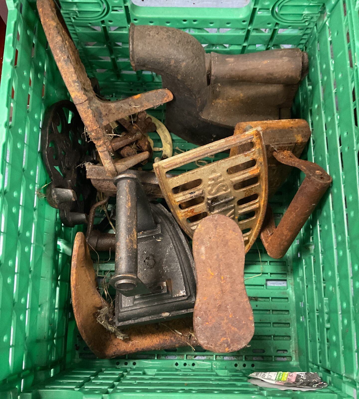 Crate of antique irons trivets and shoe last