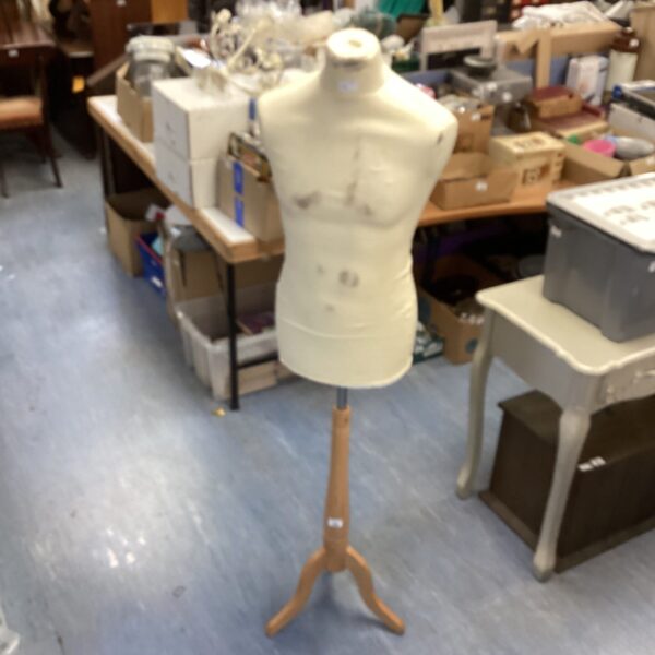 Vintage Taylor's dummy with wooden stand in workshop setting.