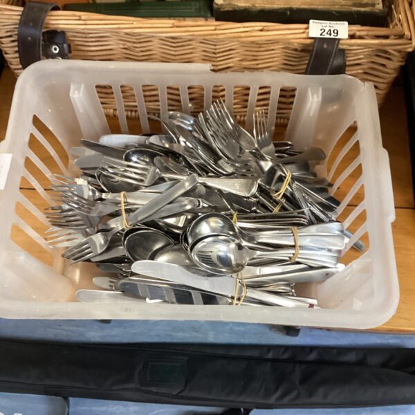Large quantity of stainless steel cutlery in a plastic container.
