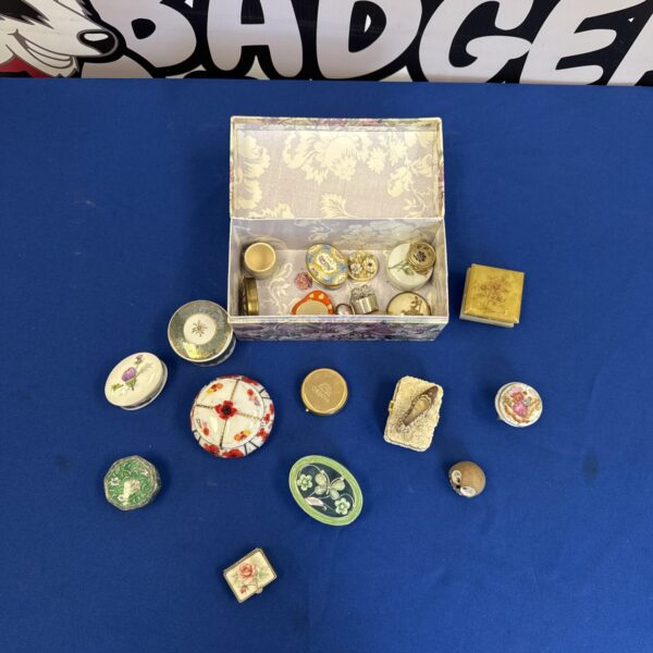 Assortment of vintage trinket pill pots on a patterned surface.