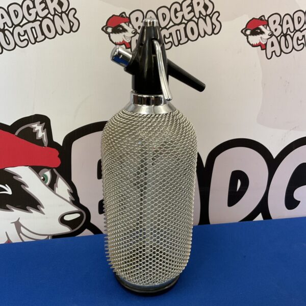 Vintage soda syphon with a distinctive mesh covering.