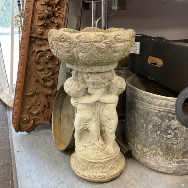Detailed concrete cherub birdbath for garden use.