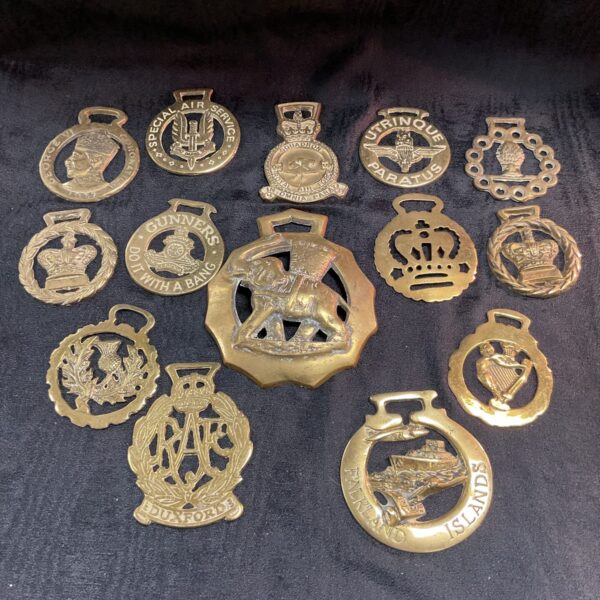 Vintage brass horse brasses with military and equestrian designs.