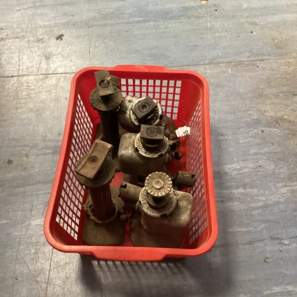 Vintage hydraulic car jacks in a red plastic crate.