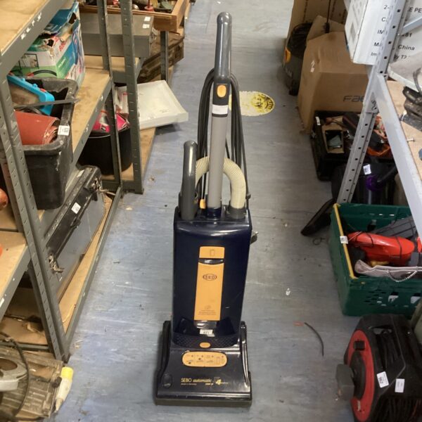 Sebo upright vacuum cleaner in a workshop setting.