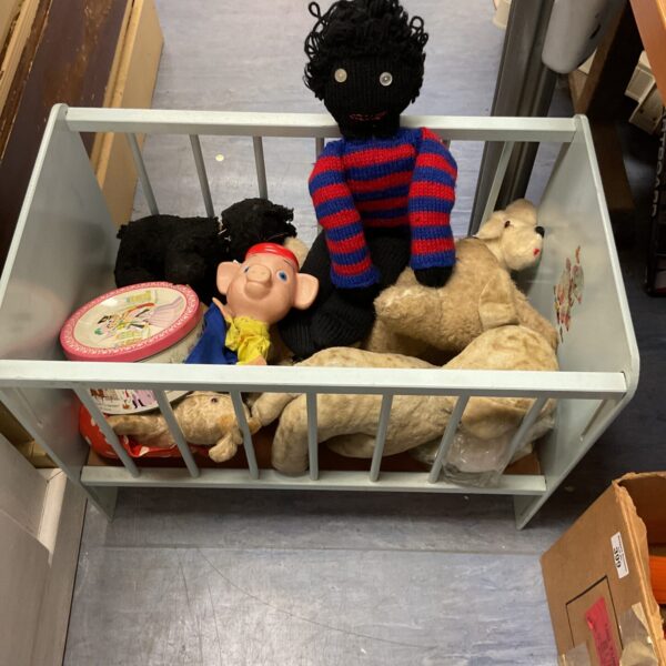 Vintage doll crib filled with antique teddy bears and soft toys.