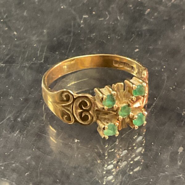 Close-up of a 9ct gold ring with four green stones.