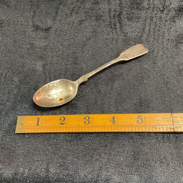 Antique Victorian silver teaspoon displayed with a ruler for scale.