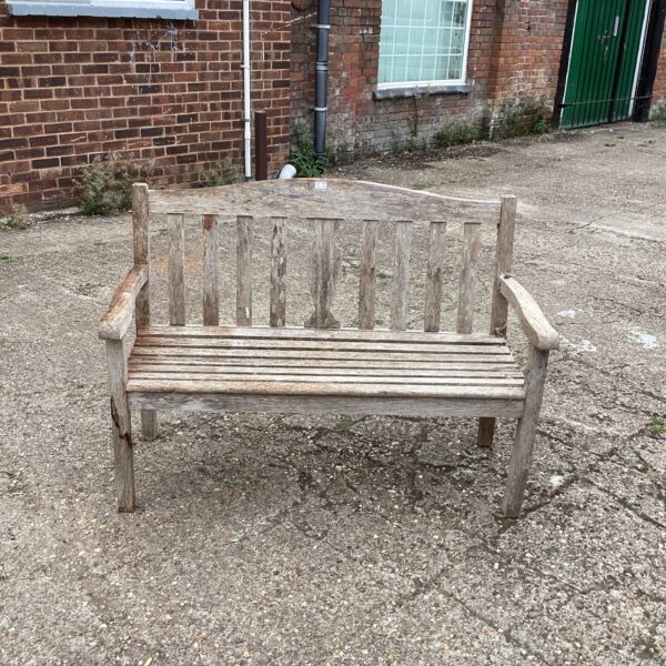 Rustic wooden garden bench in a sunny outdoor setting.