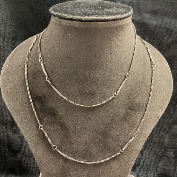 Delicate silver bar link necklace on a display bust.