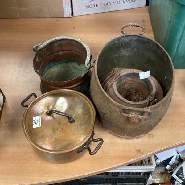 Four vintage copper pots with handles, showing aged patina.