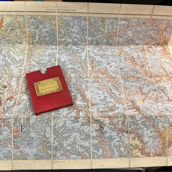 Antique geological survey map of England and Wales laid out on a tiled floor.