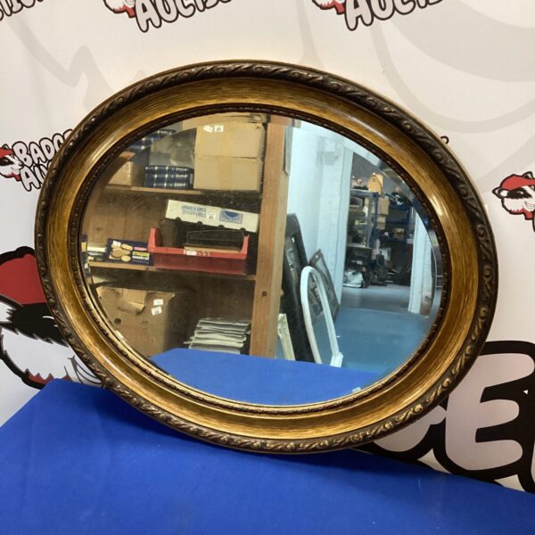 Vintage oval wall mirror with ornate gold frame, ideal for home decor.