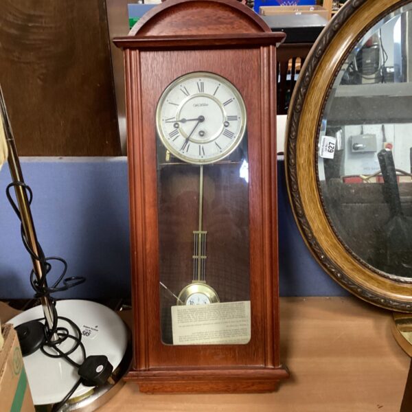 Vintage style wooden wall clock with pendulum for home decor.