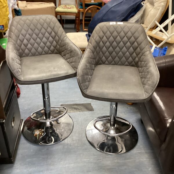 Two grey padded bar stools with chrome bases for kitchen seating.