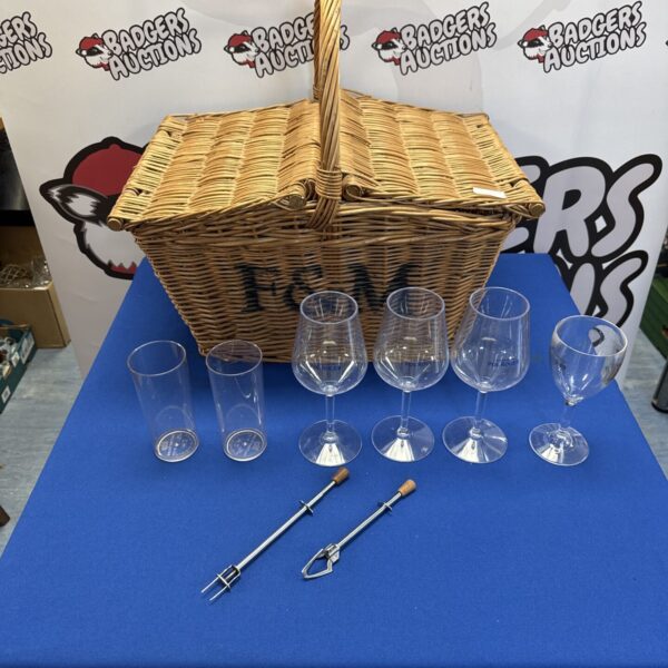 Wicker picnic hamper basket with plastic glasses and cocktail picks.