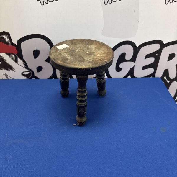 Antique oak milking stool with turned legs, rustic farmhouse style.