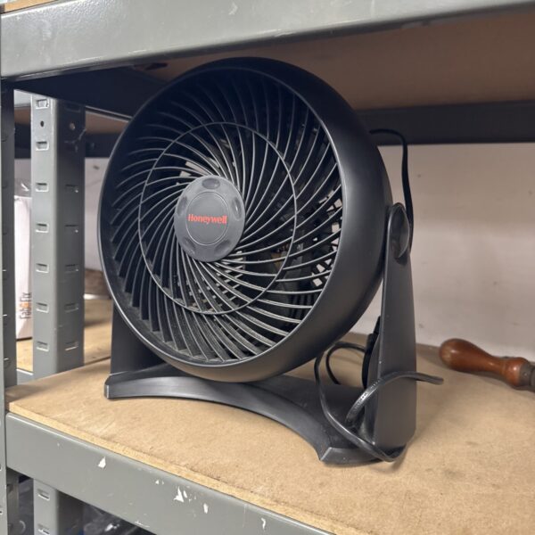 Black vintage Honeywell desk fan on a shelf.