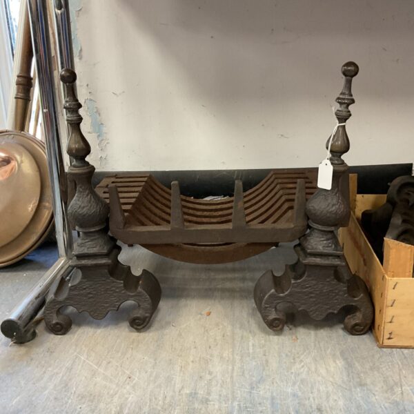 Vintage cast iron fireplace grate with decorative firedogs.