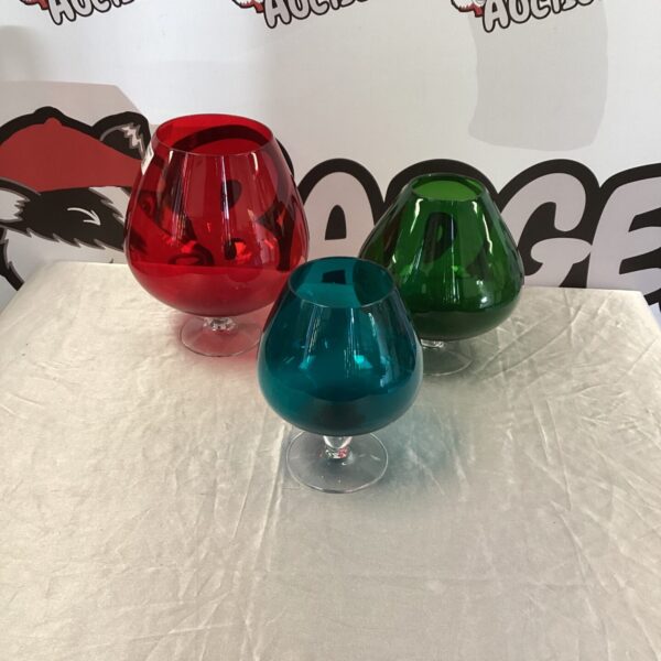 Lot of three oversized brandy glasses in red, green, and clear.