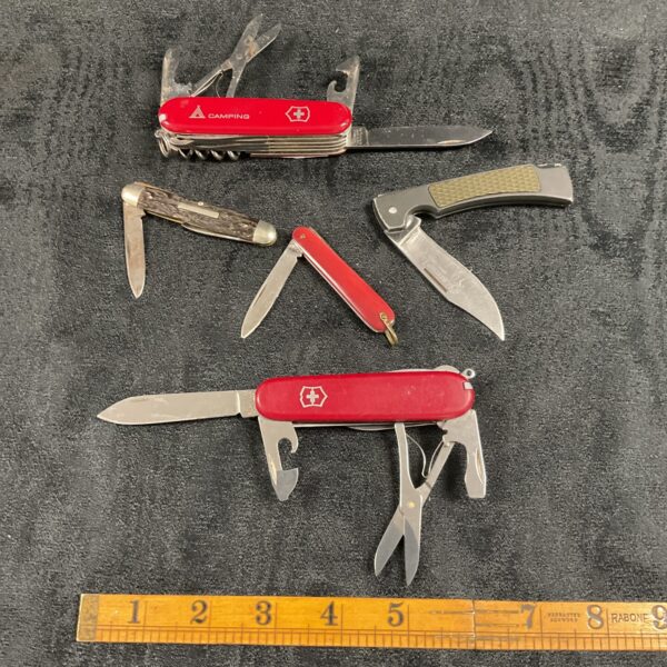 Red handled Victorinox Swiss Army knife in a lot of pocket knives.