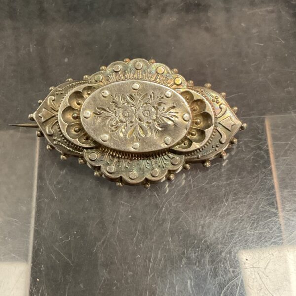Antique Victorian silver brooch with a detailed floral design.