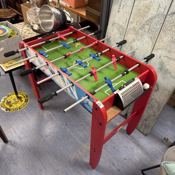 Vintage football table with red and blue players on green felt.